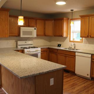 A modern kitchen with wooden cabinets, granite countertops, and stainless steel appliances.