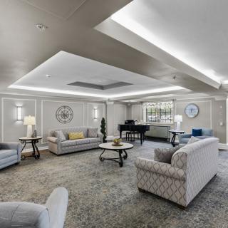 A spacious and elegantly designed living room featuring comfortable seating, a grand piano, and ambient lighting.