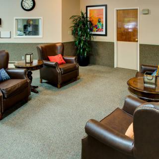 A cozy waiting room with leather chairs and a coffee table.