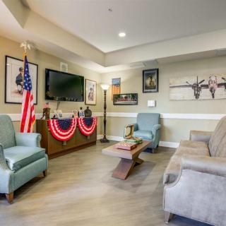 A cozy living room with a patriotic theme, featuring comfortable seating, a television, and American flag decor.