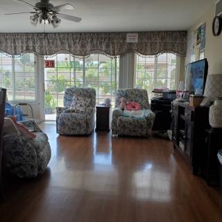A cozy living room with armchairs, a TV, and large windows letting in natural light.