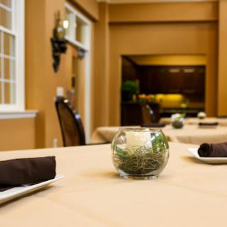 A beautifully arranged dining room featuring elegant table settings and a touch of greenery.