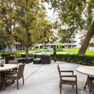 An inviting outdoor seating area with tables, chairs, and lush greenery.