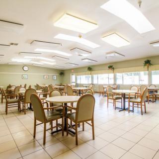 An empty dining area with multiple tables and chairs, illuminated by overhead light fixtures.