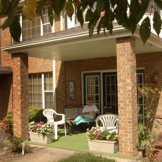 A cozy porch with chairs and plants at the entrance of a brick house.