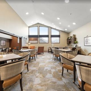 A modern dining area with tables, chairs, and large windows providing ample natural light.