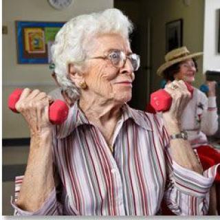An elderly woman exercising with pink dumbbells, promoting an active and healthy lifestyle.