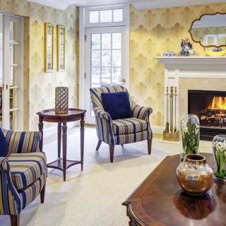 A cozy living room featuring a fireplace, armchairs, and elegant decor.