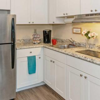 A modern kitchen with white cabinets, granite countertops, and stainless steel appliances.