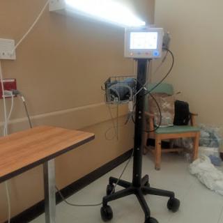 A medical monitor on a mobile stand, positioned in a hospital room.