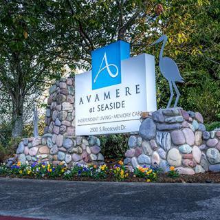 A sign for Avamere at Seaside surrounded by a rock sculpture and landscaping.