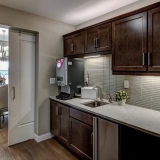 A modern kitchen with dark cabinets, a countertop with a sink, and various appliances.