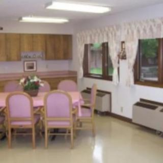 A cozy dining room with a table and pink chairs, adorned with a flower vase.