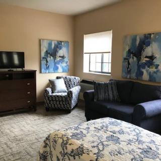 A cozy living room with modern furniture, abstract artwork, and a television.
