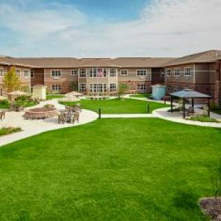 A well-maintained courtyard with green lawns and winding pathways, surrounded by a two-story brick building.