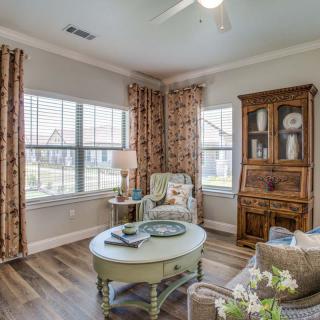 A cozy living room with a wooden cabinet, armchair, and coffee table by the window.