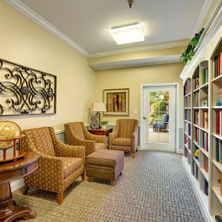 A cozy living room interior with comfortable chairs, a bookshelf, and decorative elements.