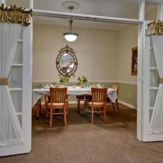 A cozy dining room with a set table, surrounded by wooden chairs and adorned with a decorative mirror on the wall.