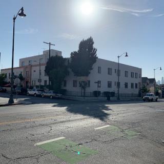 A sunny day in an urban setting, showcasing a building and street scene.