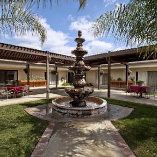 A serene courtyard featuring a beautiful fountain surrounded by palm trees and inviting seating areas.