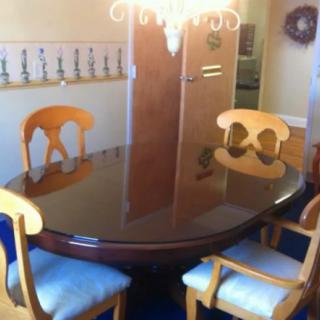 A dining room featuring a polished wooden table and matching chairs, illuminated by a chandelier.