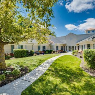 A beautiful residential house with a well-maintained garden and a pathway leading to the entrance on a sunny day.