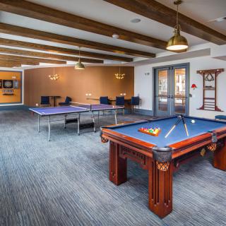 A modern game room featuring a pool table and ping pong tables for recreation.