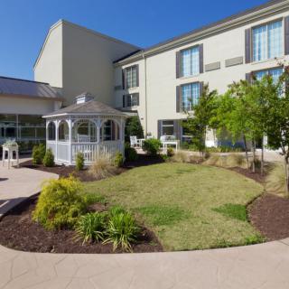 A well-maintained garden with a gazebo outside a modern building.