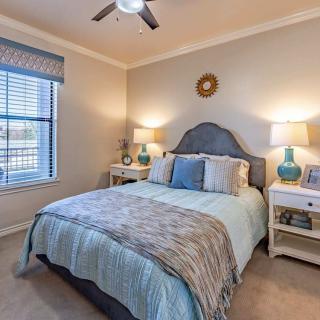 A cozy and well-decorated bedroom with a comfortable bed, two nightstands with lamps, and a window with blinds.