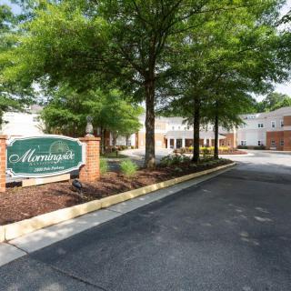 The entrance to a residential complex with a sign and well-maintained landscaping.