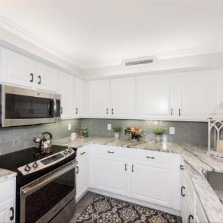 A modern kitchen with white cabinets and stainless steel appliances.