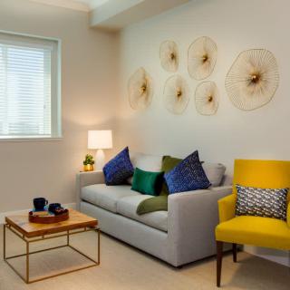 A modern living room with a stylish sofa, colorful pillows, and artistic wall decor.