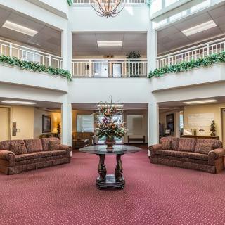 A spacious lobby area with sofas and a decorative table in the center, surrounded by balconies and greenery.