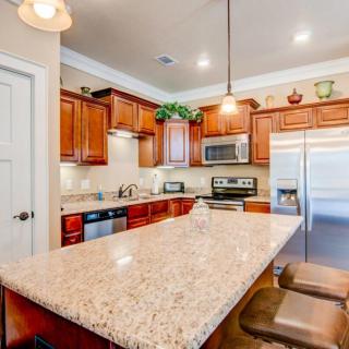 A modern kitchen with granite countertops, wood cabinets, and stainless steel appliances.