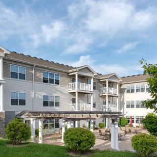 A three-story residential apartment building with balconies and a landscaped outdoor area.