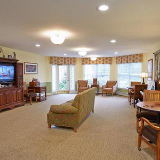 A spacious living room with comfortable seating, a TV, and large windows.