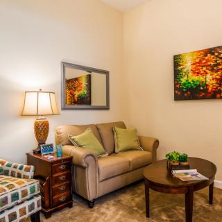 A cozy living room with a sofa, armchair, and colorful artwork.
