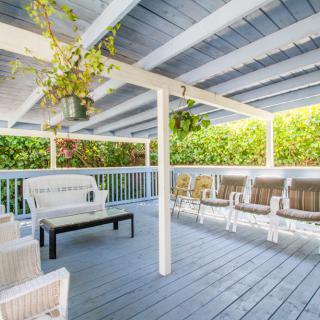 A cozy covered patio with wooden seating and hanging plants.