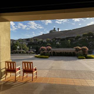 A peaceful view from a doorway featuring two empty chairs and a scenic hillside in the background.