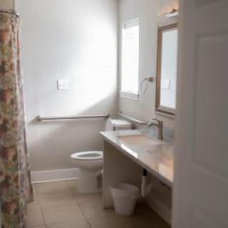 A bright bathroom featuring a toilet, sink, mirror, and a floral shower curtain.