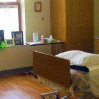 A hospital room with a single bed and medical equipment near a window.