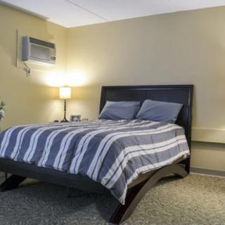 A cozy bedroom with a striped bedspread and wall-mounted air conditioner.