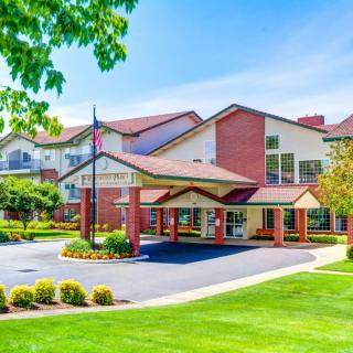 A well-maintained residential building with a lush green lawn and driveway.