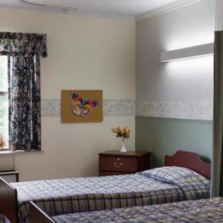 A cozy twin-bedroom setup with floral curtains and a dresser topped with a vase of flowers.