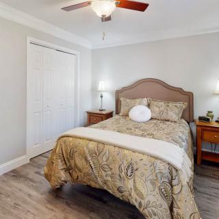 A cozy bedroom with a ceiling fan, bed, and nightstands.