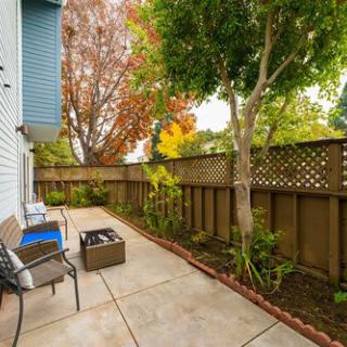 A cozy patio area with seating and a fenced garden.