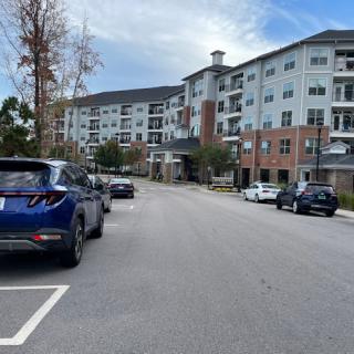 A view of an apartment building with parked cars in a residential area.