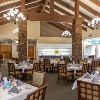 A spacious restaurant interior with elegantly set tables and modern chandeliers.