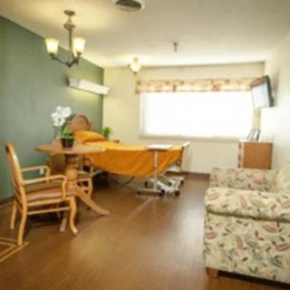 A well-furnished hospital room with a patient bed, seating area, and natural lighting.