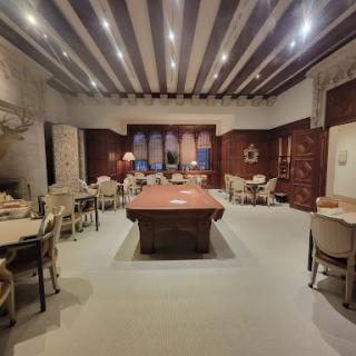 A spacious modern dining room featuring a large wooden table surrounded by elegant chairs, illuminated by soft lighting.